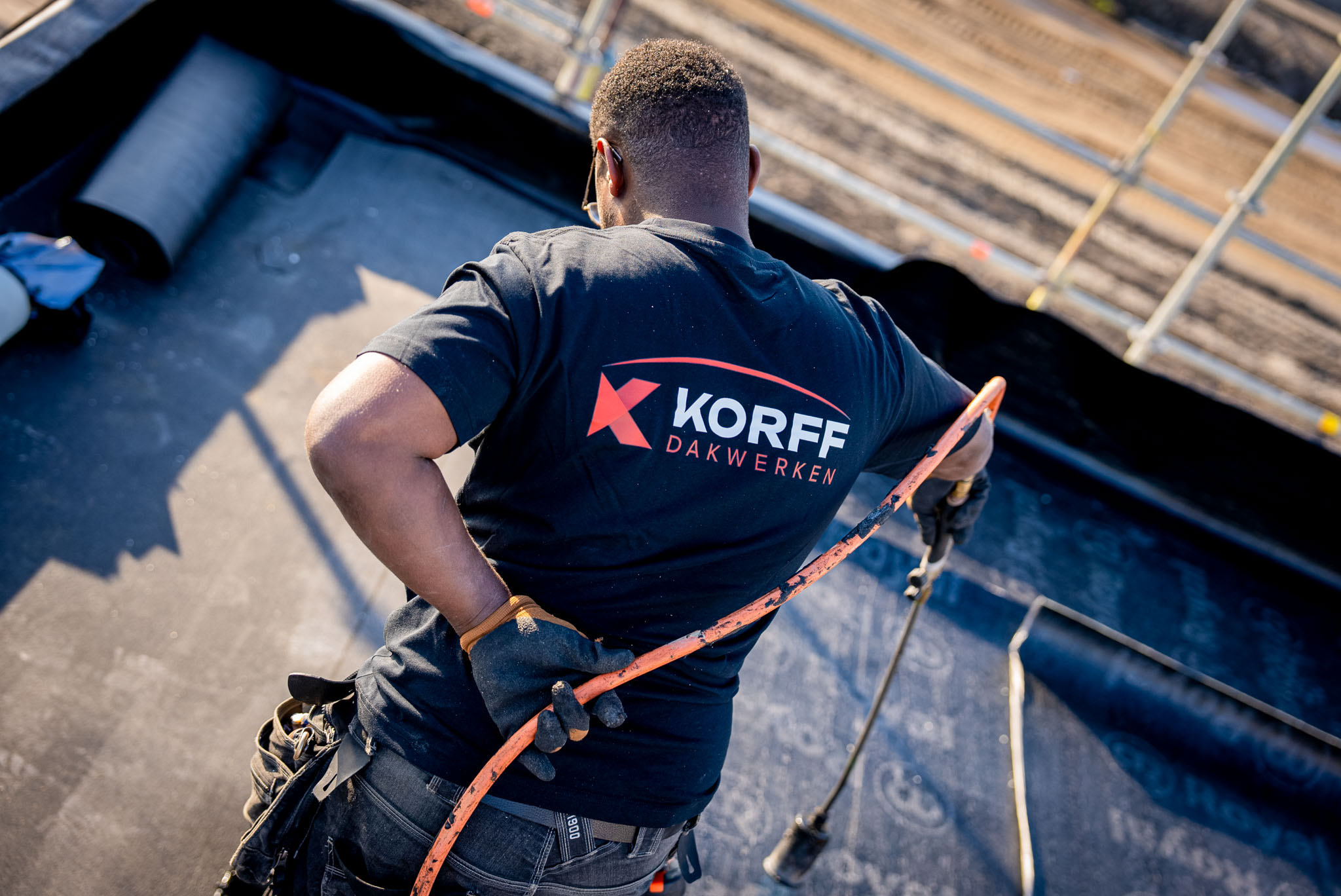 Dakdekker van Korff Dakwerken werkt met een brander aan de dakbedekking van een plat dak.